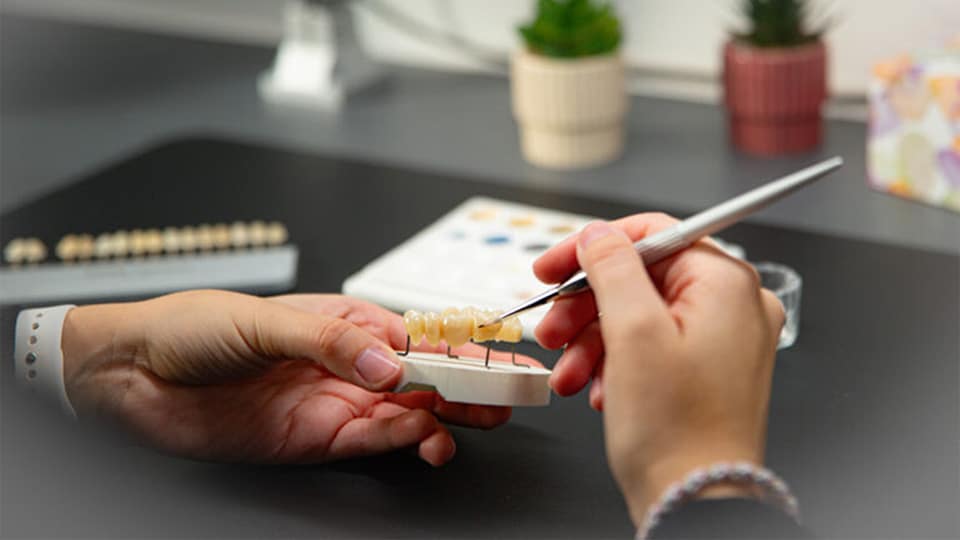 Zahntechnikerin im Dentallabor von blendent Zahnärzte Paderborn bei der individuellen Farb- und Formanpassung von hochwertigem Zahnersatz für Smile Design und Implantate.